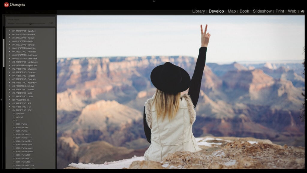 Woman sitting on rocks with Grand Canyon in background, making peace sign.