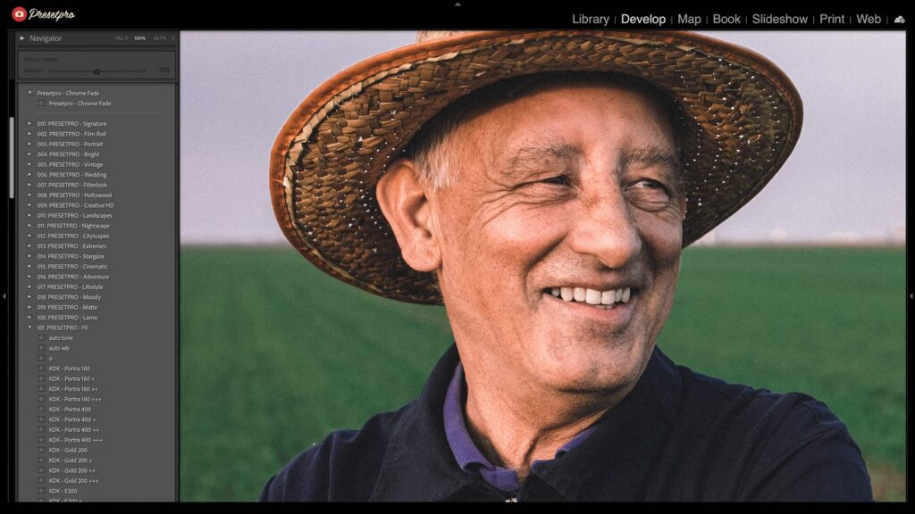 Smiling elderly man in a straw hat outdoors with a green background.