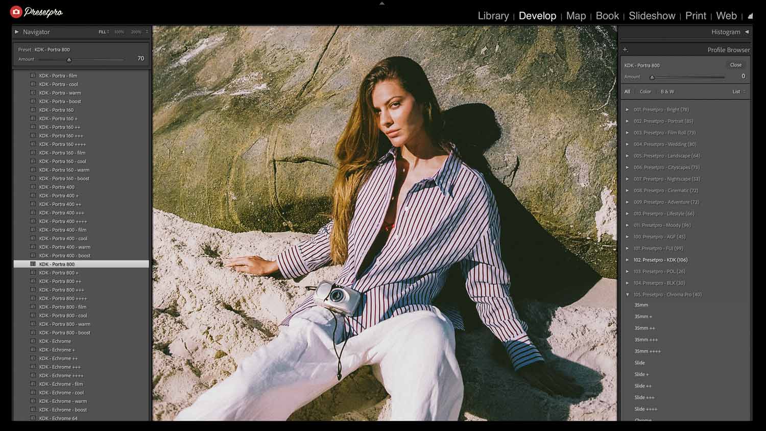 Woman in pinstriped shirt holding vintage camera on weathered stone wall, warm Kodak Portra 800 film emulation with golden skin tone rendering and natural grain.